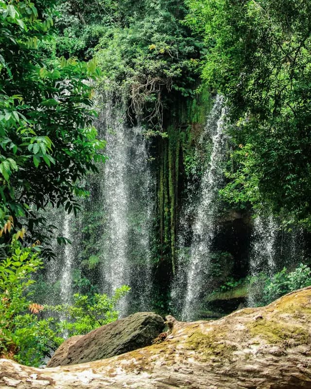 A waterfall falling through thick green forest at Phnom Kulen
